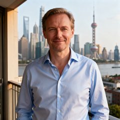 德籍企业高管Markus Weber的肖像照，他穿着浅蓝色衬衫，站在公寓阳台上，身后是上海城市景观。